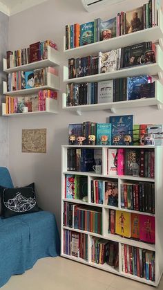 a book shelf filled with lots of books next to a blue couch