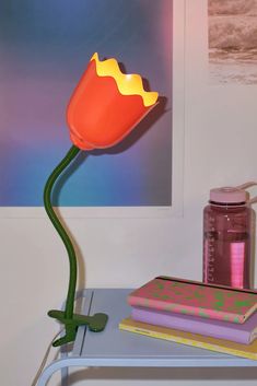 a lamp that is on top of a table next to some books and a cup