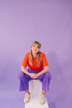 a woman sitting on top of a white stool