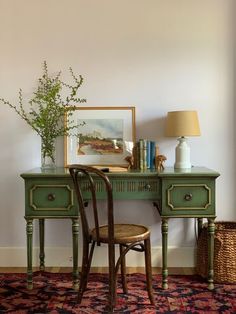 a green desk with two chairs and a painting on the wall