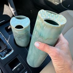 two green vases sitting on top of a car dashboard next to a cup holder