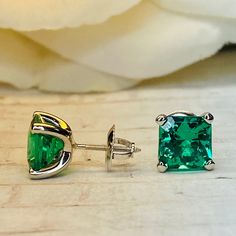 "The stud earrings pictured are lab created emerald #7066 Approximate total carat weight: approx. 3.50ctw diamond equivalent -Center Stone Size: 7x7mm - approx. 1.75ct each diamond equivalent -Center Stone Shape: radiant cut -Gem Type: lab created emerald -Stone Clarity: AAA -Stone Color: Red -Moh's Scale: 9 hardness -Metal Type and Purity: 14k white gold -Setting: 4 prong open u -Backing: friction back (earring backs are subject to change due to availability) -Country of Manufacturing: USA (Mic Emerald Cut Green Sterling Silver Earrings, Emerald Round Cut Earrings For Anniversary, Round Cut Emerald Earrings For Anniversary, Classic Emerald Earrings For Anniversary, Gia Certified Green Earrings In Fine Jewelry Style, Gia Certified Green Earrings Fine Jewelry, Green Prong Setting Earrings For Gift, Gia Certified Green Fine Jewelry Earrings, Green Gia Certified Fine Jewelry Earrings