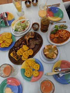 a table topped with plates and bowls filled with different types of food next to drinks