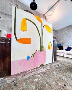 a large painting on the wall in a room with wood flooring and white couches