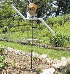 a scarecrow head on top of a pole in the middle of some grass and rocks