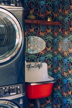 a washer and dryer in a small room with colorful wallpaper on the walls