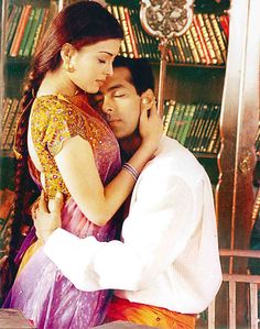 a man and woman embracing each other in front of a bookshelf full of books