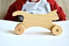 a small wooden cat toy sitting on top of a table next to a little boy