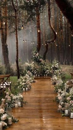 an outdoor ceremony setup with flowers and candles on the ground, surrounded by trees in the background