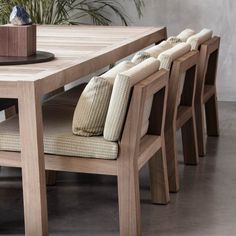 a wooden table with four chairs and a potted plant in the corner on top