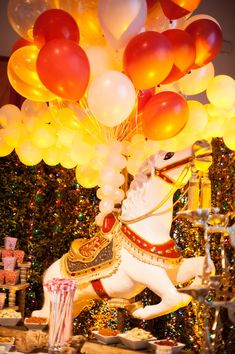 a white horse with balloons attached to it's back in front of a christmas tree