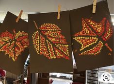 three paintings are hanging on clothes pins in the shape of leaves with beads attached to them