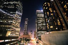 the city is lit up at night with skyscrapers and street lights in the foreground