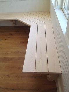 a wooden bench sitting in front of a window on top of a hard wood floor