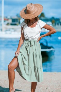 Infuse your summer with charm in our White Eyelet Flutter Top & Sage Skirt Midi Dress. Featuring delicate eyelet detailing, flutter sleeves, and a flowing sage skirt, this dress exudes casual cool vibes. Featured Line: SEA Product code: CAA05A4C006CP Features:  Knit Scoop neckline  Short flutter sleeves  Waist tie  Midi  A-shape silhouette Wash Method: Regular Wash Material: 100%RAYON. Sage Midi Dress For Summer, Sage Casual Dress For Brunch, Summer Dresses With Flowy Skirt And Flutter Sleeve, Sage Dresses For Summer Beach, Casual Green Tiered Skirt Dress, Summer Short Sleeve Sage Dress, Chic Sage Summer Dress, Short Sleeve Sage Summer Dresses, Sage Midi Length Summer Dress