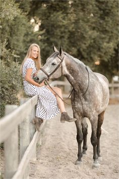 a woman sitting on top of a horse next to a fence