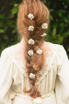 a woman with long red hair and flowers in her hair is seen from the back