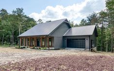 a house in the woods with lots of trees and gravel on the ground next to it