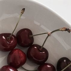 a white bowl filled with cherries on top of a table