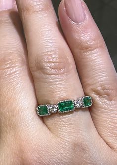 a woman's hand with an emerald and diamond ring