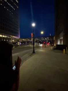 a person taking a photo on their cell phone in the city at night with buildings and street lights