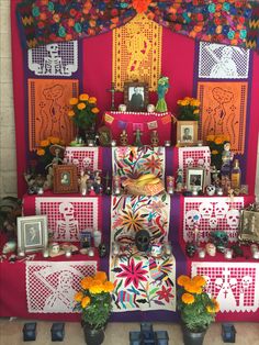 an altar with flowers and pictures on the wall in front of it is decorated with mexican folk art