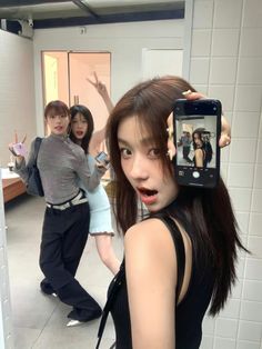 a woman taking a selfie with her cell phone in front of her and two other women behind her