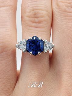 a woman's engagement ring with an oval blue sapphire surrounded by three smaller diamonds