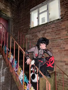 a woman sitting on top of a stair case next to a black and white cat