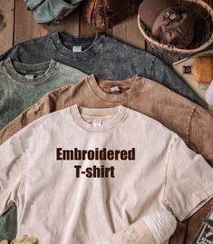 three t - shirts with the words embroidered on them next to shoes and other items