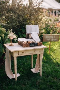 a table with books and flowers on it in front of a sign that says welcome to the bride