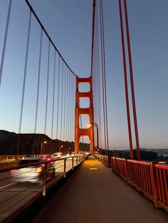 cars drive over the golden gate bridge at dusk