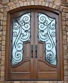 two double doors with decorative iron work on the front and side panels, set against a stone wall