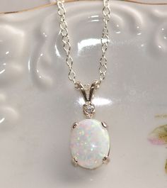 "A lovely necklace made using lab created opal and crystal clear, sparkling Cubic zirconia. The opal is hand-set in to a solid sterling silver prong setting. The opal measures 10mm long and pendant measures 3/4\" long. It hangs from solid sterling silver chain. Necklace closes with a sterling silver clasp. Please choose necklace length at checkout. See matching earrings here: https://www.etsy.com/listing/182355302/australian-opal-gemstone-earringsdiamond? SEE MATCHING BRACELET HERE: https://www. Classic White Opal Jewelry, White Sparkling Stone Round Pendant Jewelry, White Sparkling Stones Round Pendant Jewelry, White Jewelry With Sparkling Stones In Round Pendant, White Opal Anniversary Necklace, Dazzling White Gemstone Necklace, White Oval Opal Necklace, Opal Pendant Necklace Vintage, Silver Prom Jewelry