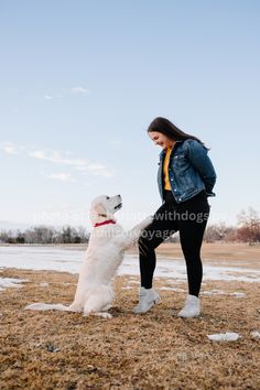 a woman is playing with her dog in the snow