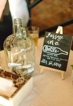 a table topped with bottles and marshmallows next to a chalkboard sign