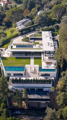 an aerial view of a house with a swimming pool in the foreground and lots of trees surrounding it