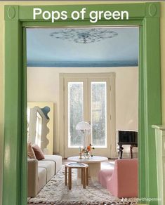 an open door leading to a living room with green walls and white furniture in it