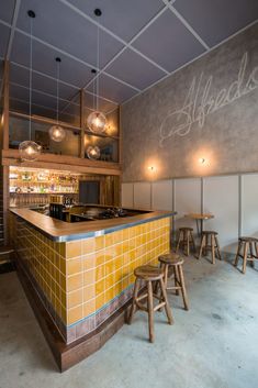 an empty bar with stools in front of it and lights hanging from the ceiling