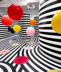 an art installation with black and white striped walls, balloons floating in the air above it