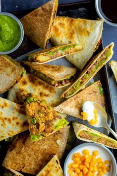 several quesadillas on a tray with corn and salsa