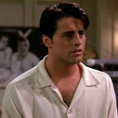 the young man is wearing a white shirt and standing in front of a kitchen counter