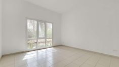 an empty room with tile flooring and large windows in the corner, all white