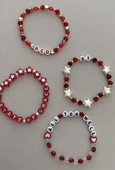 three red, white and gold beaded bracelets with the word peace written on them