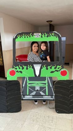 a woman and her daughter are in a monster truck made out of cardboard with tires