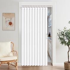 a living room with white curtains and a chair in front of the sliding glass door