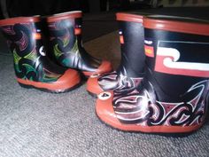 three pairs of black and orange boots with designs on them sitting on the floor next to each other