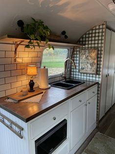 a kitchen area with sink, stove and oven in an airstream style vehicle that is parked on the street