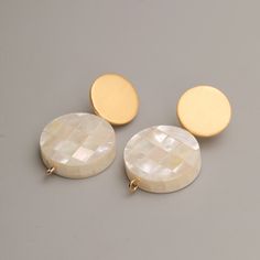 A perfect fusion of elegance and sophistication. These exquisite earrings feature lustrous, hand-selected Mother of Pearl pieces, carefully crafted into mesmerizing round shapes that showcase the natural iridescence and beauty of this precious material. Each earring is meticulously set on a 925 silver stud, ensuring both durability and a touch of timeless elegance. The matt finish gold perfectly complements the ethereal allure of the Mother of Pearl, creating a stunning contrast that will catch Affordable Gold Mother Of Pearl Jewelry, Modern Gold-tone Clip-on Earrings As Gift, Modern Gold Pearl Earrings, Elegant Pierced Jewelry In Mother Of Pearl, Elegant Mother Of Pearl Jewelry, Modern Round Earrings With Elegant Design, Modern Gold-tone Earrings For Anniversary, Elegant Solitaire Mother Of Pearl Earring, Elegant Single Mother Of Pearl Earring