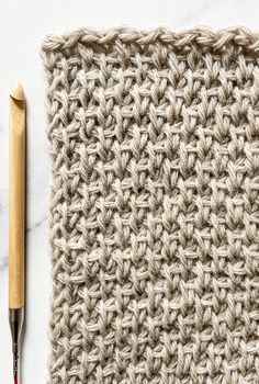 the crochet pattern is next to a pencil on top of a piece of cloth